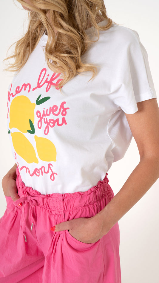 Detailansicht Print Shirt in gelb Pink: cooles ausgefallenes T-Shirt in weiß mit pinker Schrift und gelben Zitronen. Dazu trägt das Model eine sommerlich lässige Stoffhose in knalligem Pink