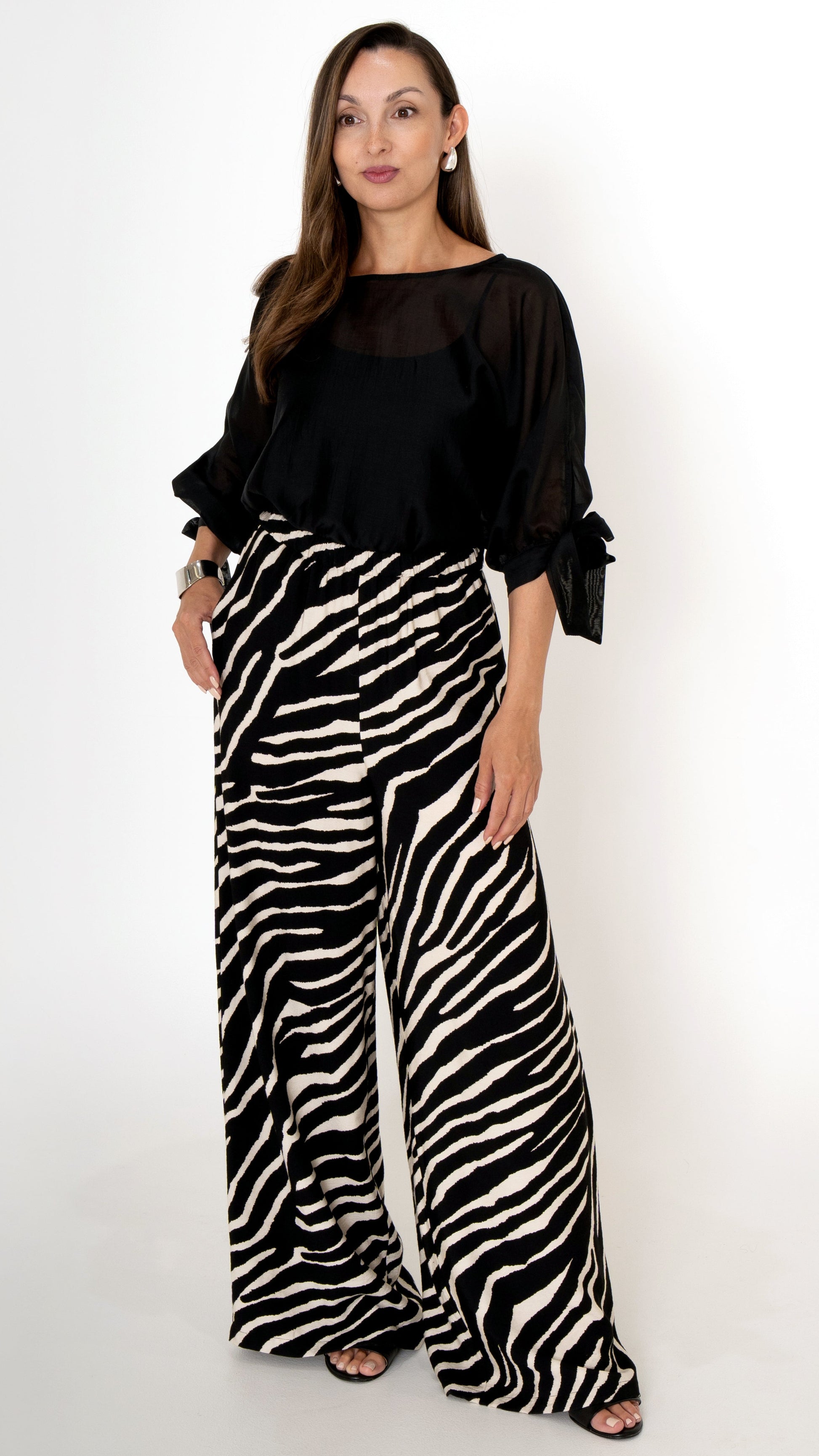 elegante ausgefallene Damenbekleidung in schwarz weiß: Modisch sommerliches Outfit bestehend aus einer weiten Zebra Print Hose und einer schwarzen Chiffonbluse  mit Schleifen am Ärmel, Halbarm