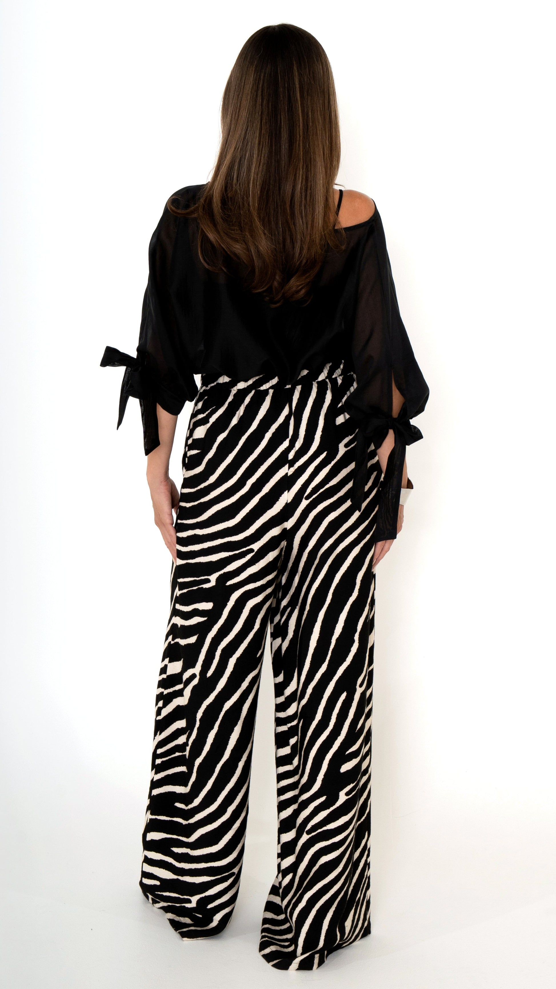 Rückansicht elegante ausgefallene Damenmode : weite lange Hose mit Zebra Animal Print und als Oberteil eine weite leicht transparente Chiffon Bluse mit Schleifen am Ärmel