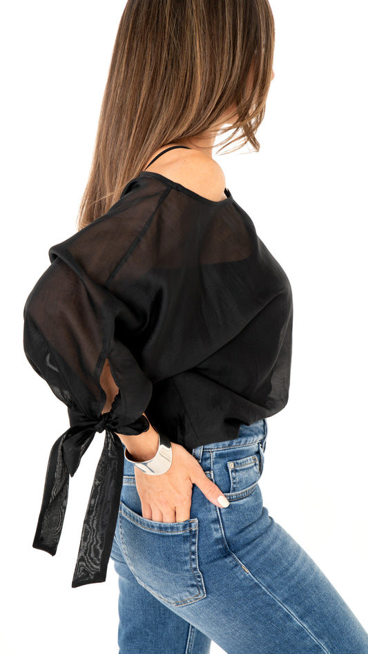 Seitenansicht Damemode: Cooles Outfit aus blauer Jeanshose und weite schwarze Bluse , halbtransparent und Schleifendetail am Ärmel