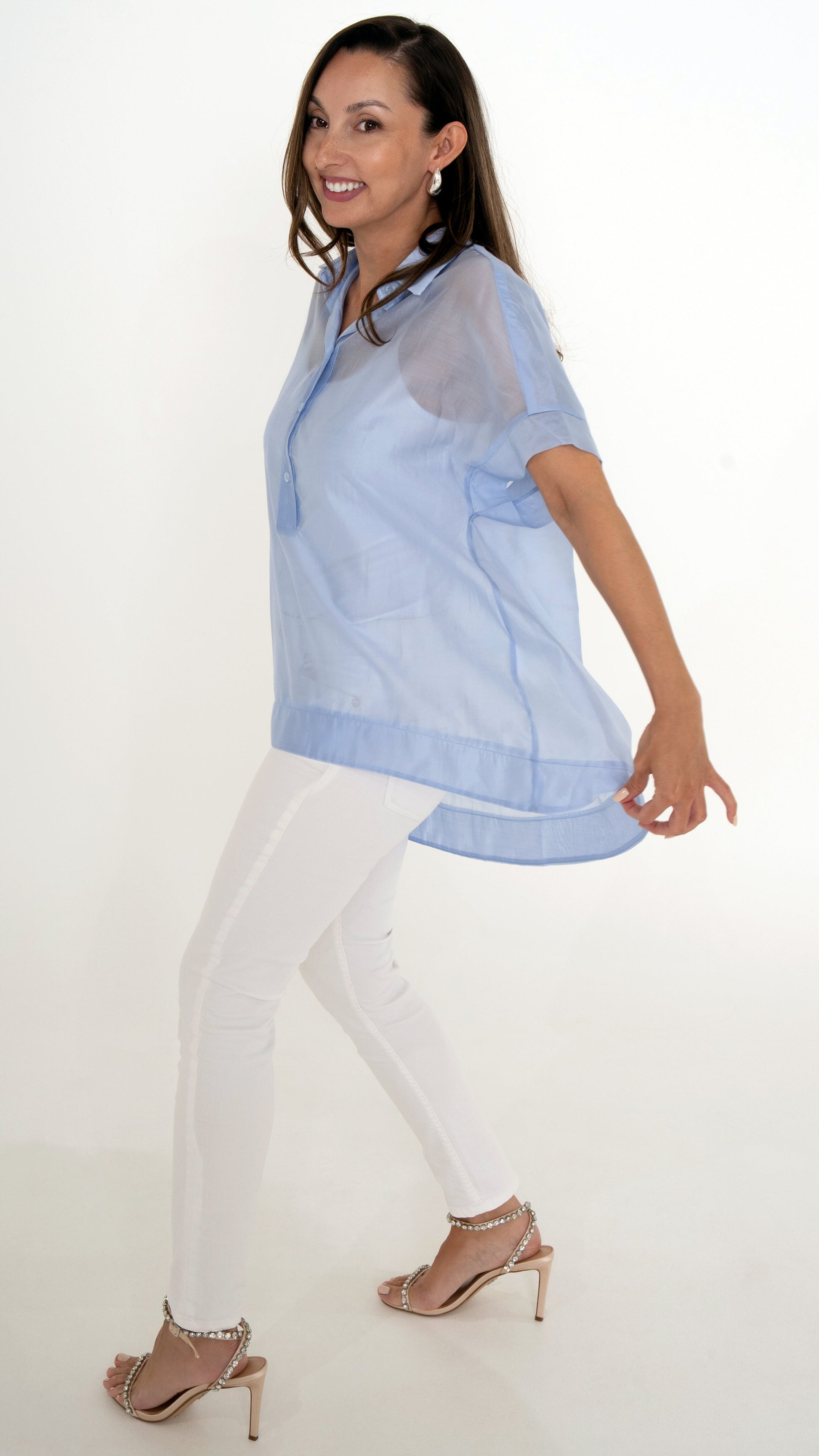 Seitenansicht feminine Damenmode: sommeroutfit bestehend aus weißer Skinny Denim, Glitzer Sandalette und lange schwingende Chiffonbluse in hellblau, leicht transparent