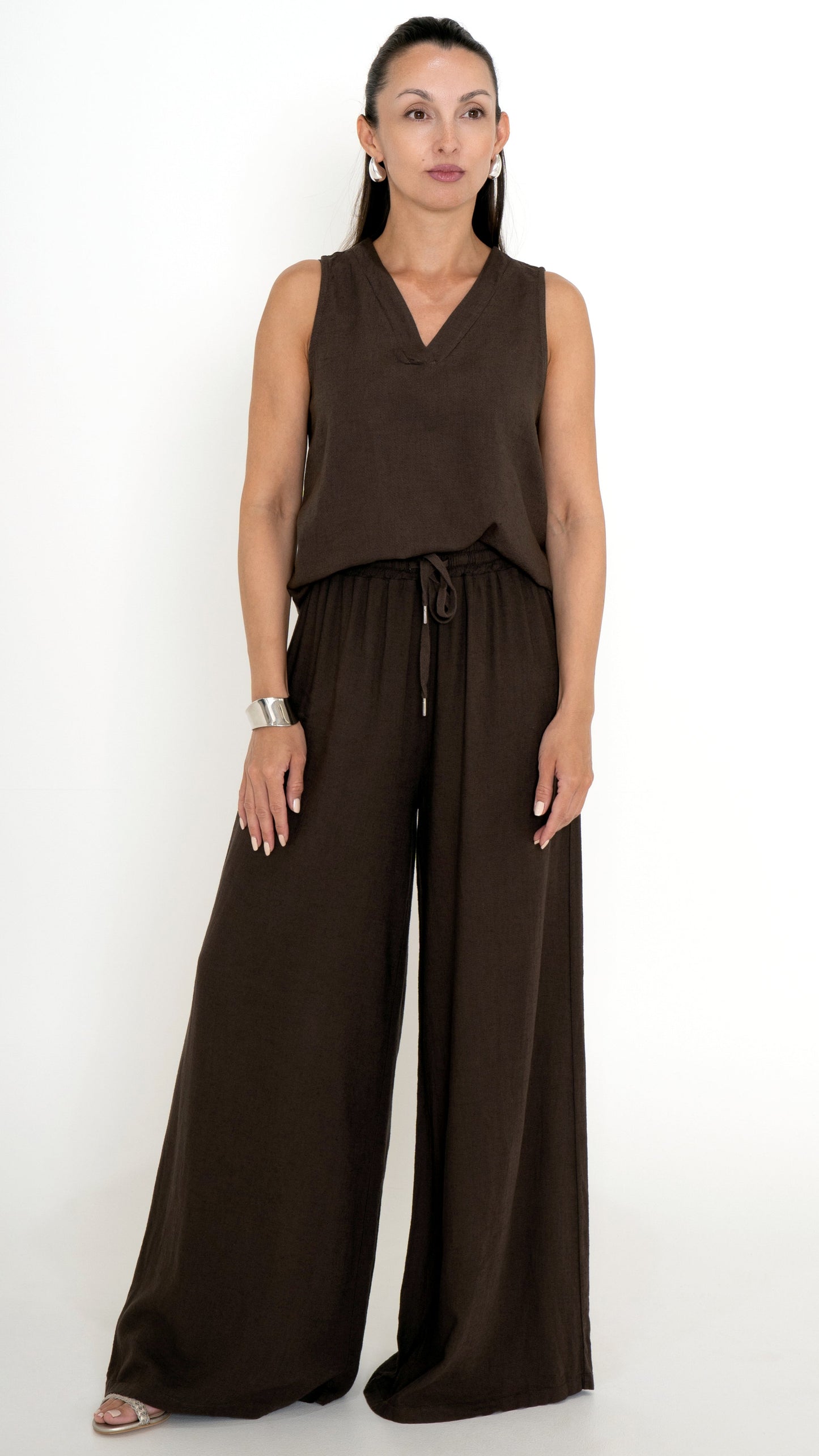 Feminine Damenmode für den Sommer in Mocca Braun: Model trägt ein braunes Outfit aus Leinen bestehend aus einer weiten Stoffhose und einem  farblich passenden Top mit V-Ausschnit, ärmellos.