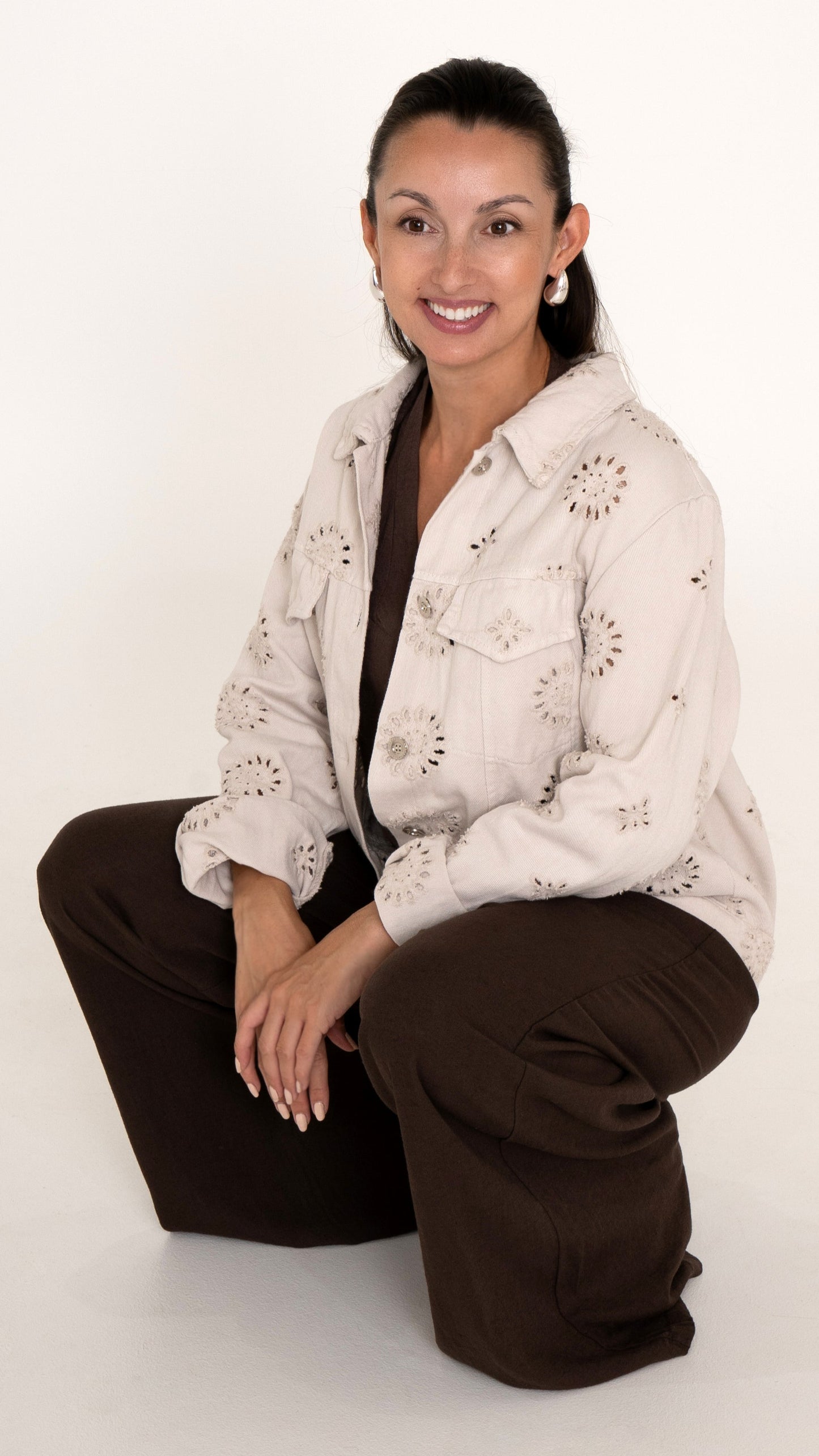 Fashion Editorial feminine Damenmode für den Sommer: Weite Denim Jacke mit floraler Lochstickerei in beige. Dazu eine Braune weite Hose