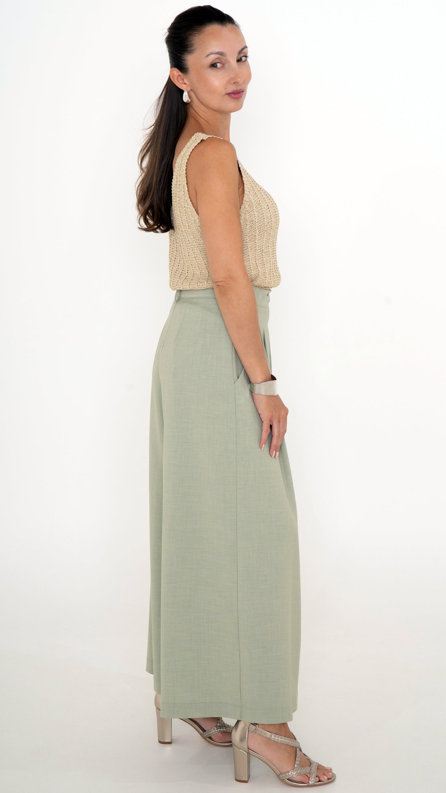 Seitenansicht von eleganter Damenbekleidung: schickes Sommeroutfit bestehend aus einer Stoffhose mit extra weitem Bein in maigrün und einem goldenen Glitzer Stricktop