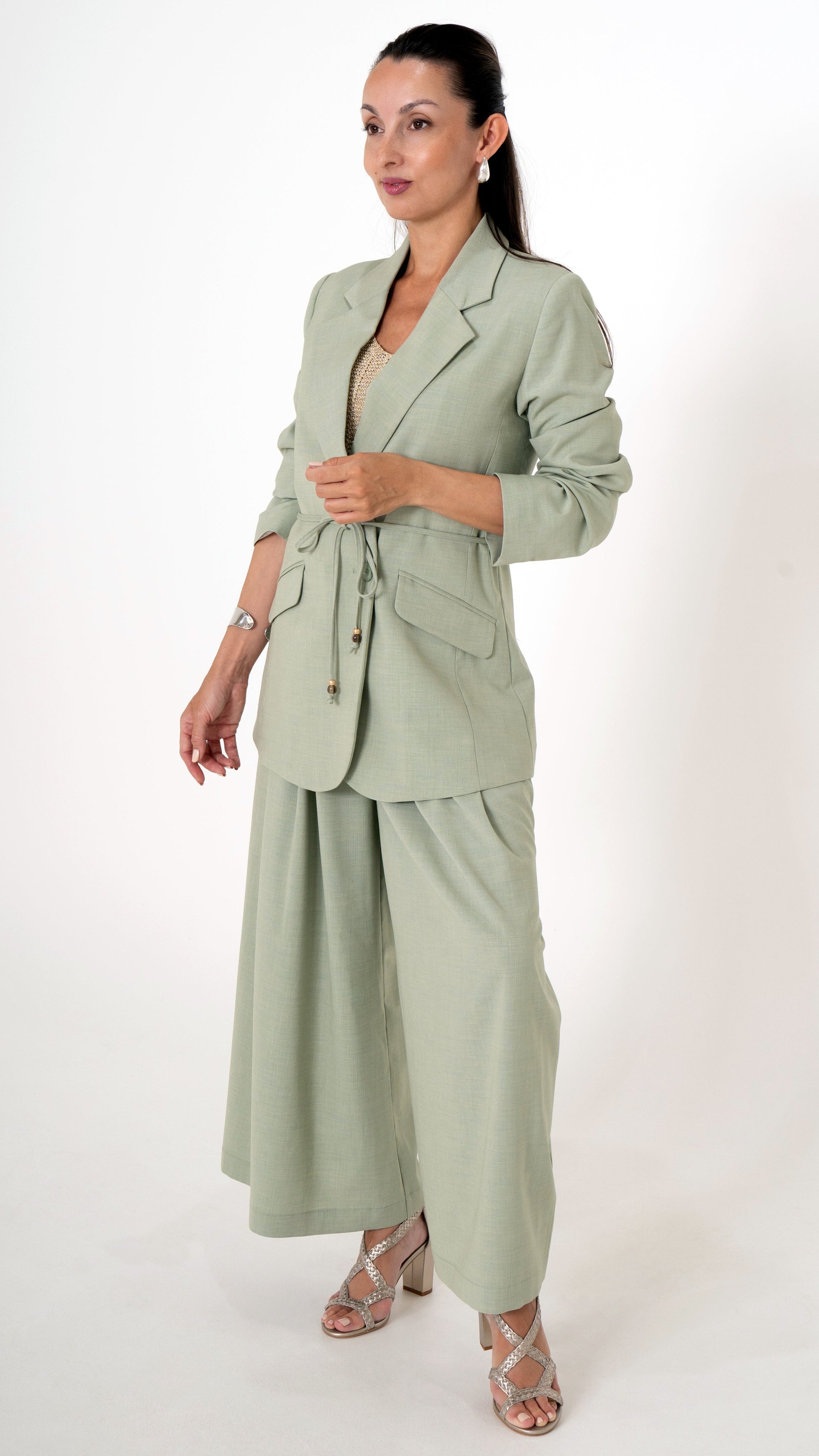 Ausgefallene Damenbekleidung bestehend aus einem stilvollem Outfit in der Farbe soft may green: weite Stoffhose in verkürzter Culotte Form. Langer Blazer mit Gürtel und Perlendetail