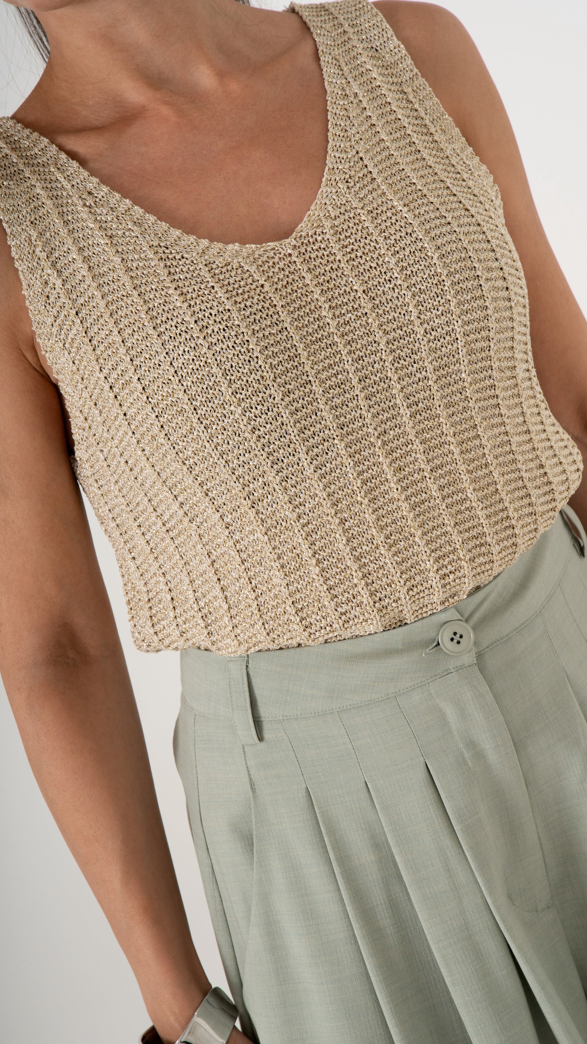 Detailansicht sommerliche Damenmode feminin: Stricktop aus goldenem Glitzer Strick, Ärmellos und Bundfaltenhose in Farbe soft maygreen